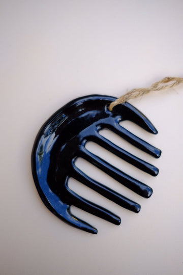 Black metal comb hanging on a white background